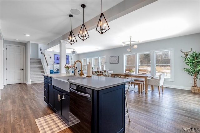 kitchen featuring dishwasher, a sink, light countertops, dark wood-style flooring, and healthy amount of natural light