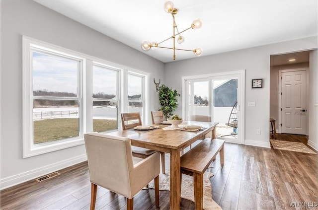 dining room featuring a chandelier, wood-type flooring, and baseboards
