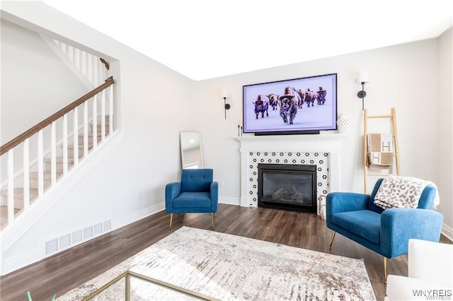 living area featuring stairs, wood finished floors, a tile fireplace, and baseboards