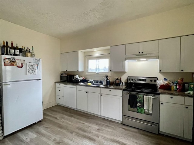 kitchen with under cabinet range hood, white appliances, light wood-style flooring, and dark countertops