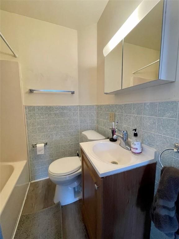 full bath with vanity, a wainscoted wall, toilet, wood finished floors, and tile walls