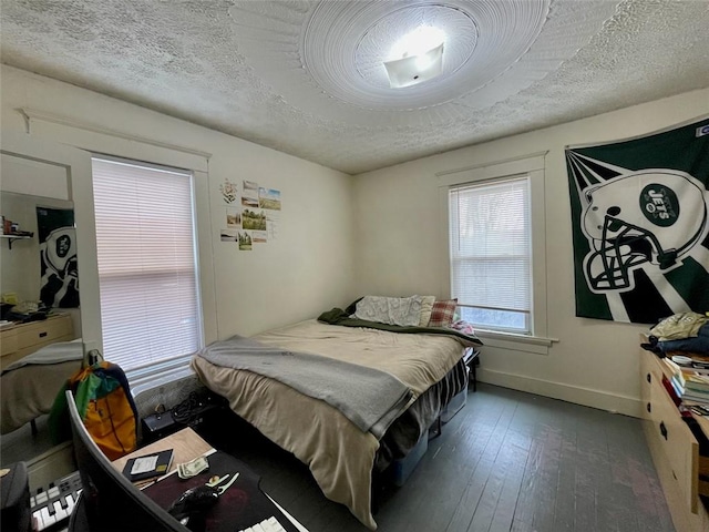 bedroom with baseboards, hardwood / wood-style flooring, and a textured ceiling