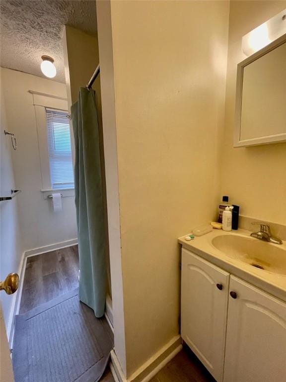 full bathroom with baseboards, a shower with curtain, a textured ceiling, vanity, and wood finished floors