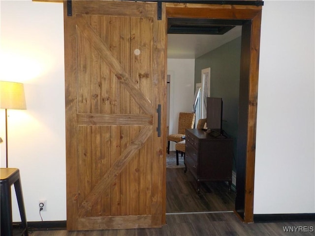 interior space with a barn door, baseboards, and wood finished floors