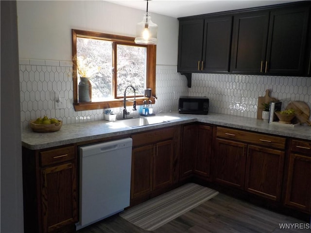 kitchen featuring dishwasher, a sink, light countertops, black microwave, and wood finished floors