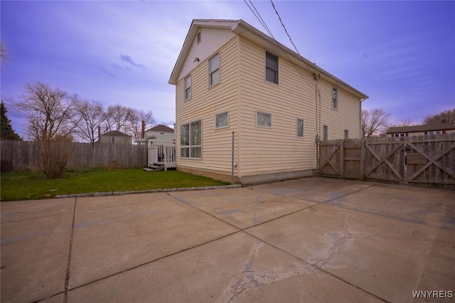 523 76th St, Niagara Falls, NY 14304 - back of property at dusk with a lawn, a gate, a patio area, and fence