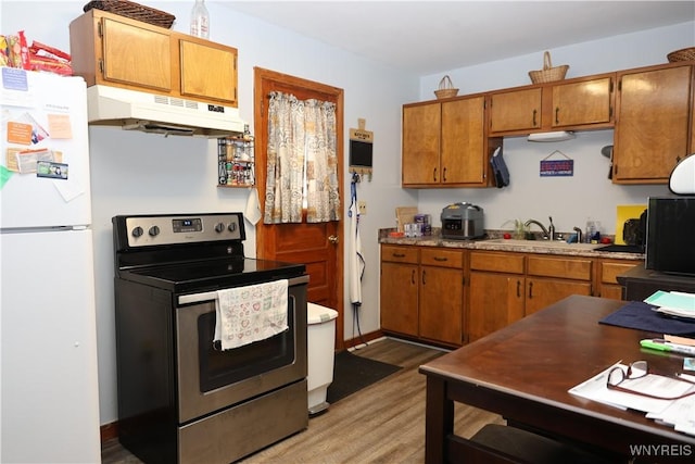 42 Mechanic St, Collins, NY 14070 - kitchen with stainless steel electric range, freestanding refrigerator, under cabinet range hood, brown cabinets, and light wood finished floors