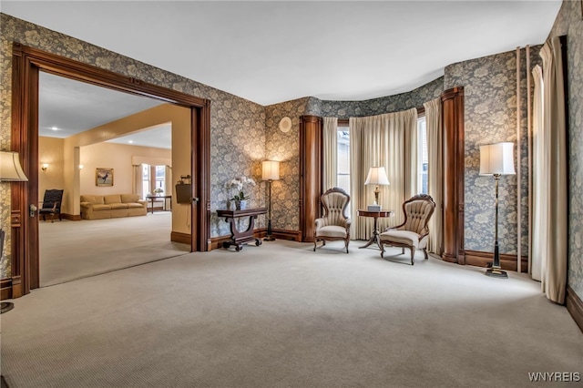 living area featuring carpet, baseboards, and wallpapered walls