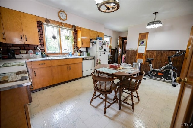 kitchen featuring light countertops, a wainscoted wall, white appliances, and light floors