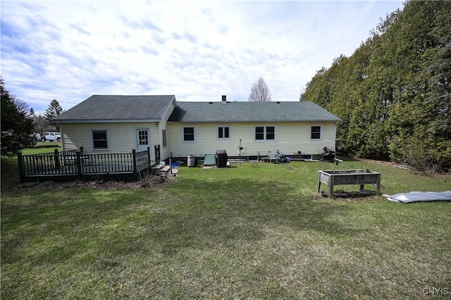 rear view of property featuring a garden, a deck, and a lawn