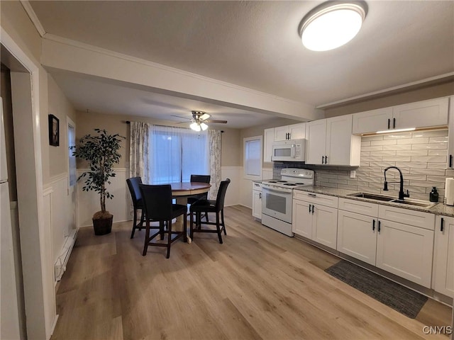 kitchen with a sink, a ceiling fan, white appliances, white cabinetry, and a baseboard heating unit