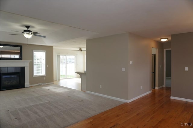 4828 Lighthouse Village Cir, Clay, NY 13088 - unfurnished living room featuring baseboards, a tiled fireplace, visible vents, ceiling fan, and wood finished floors