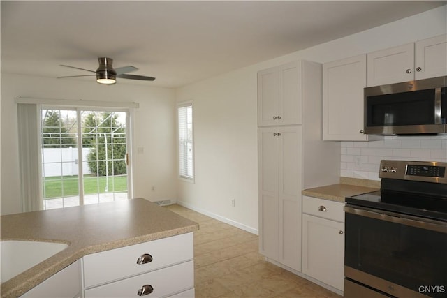 4828 Lighthouse Village Cir, Clay, NY 13088 - kitchen featuring a sink, ceiling fan, white cabinetry, stainless steel appliances, and backsplash