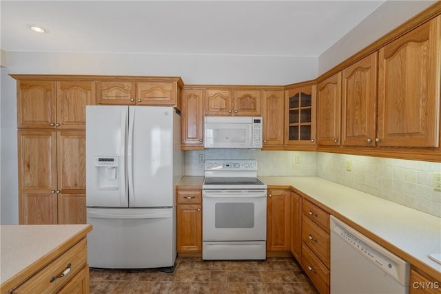 kitchen with light countertops, glass insert cabinets, decorative backsplash, and white appliances
