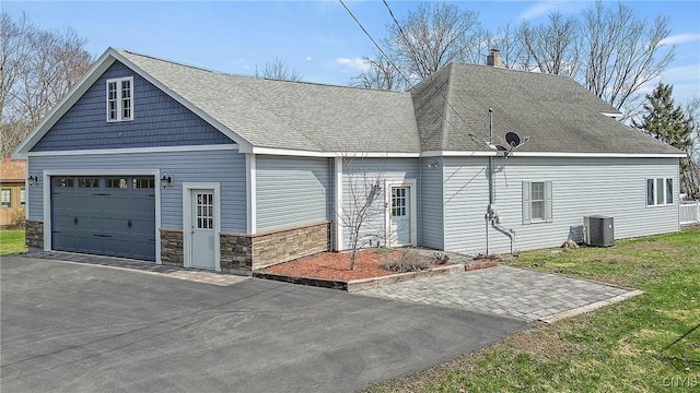 exterior space with a chimney, aphalt driveway, cooling unit, stone siding, and a garage