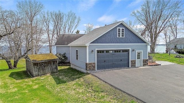 view of side of property featuring an outdoor structure, a lawn, stone siding, and aphalt driveway