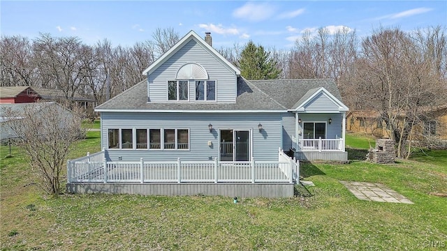 back of house with a shingled roof, a chimney, and a yard