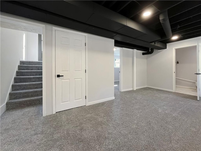finished basement featuring carpet floors, baseboards, and stairway