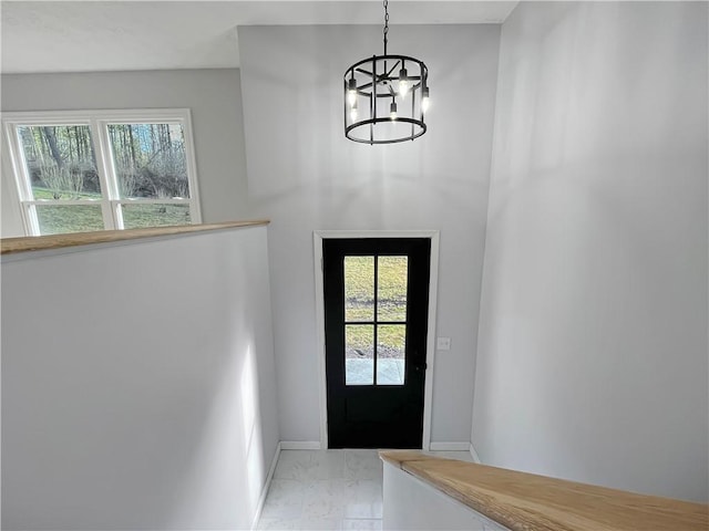 entryway with a wealth of natural light, baseboards, marble finish floor, and an inviting chandelier
