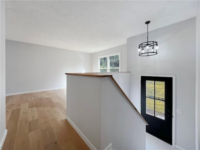 foyer entrance featuring a chandelier, a wealth of natural light, light wood-type flooring, and baseboards