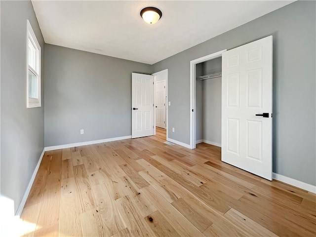 unfurnished bedroom featuring light wood-type flooring, a closet, and baseboards