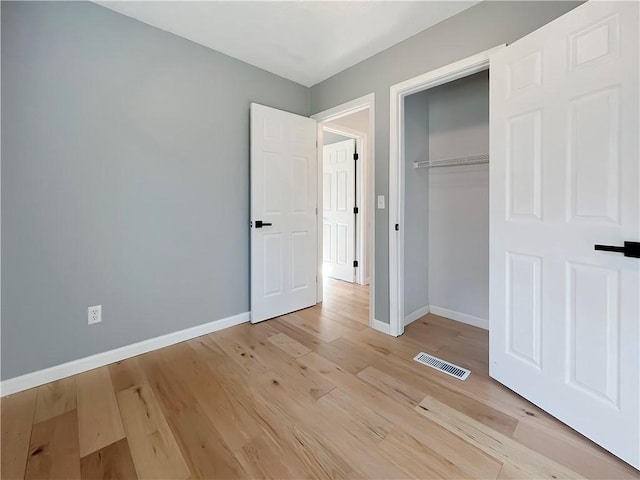 unfurnished bedroom with light wood-style flooring, visible vents, baseboards, and a closet
