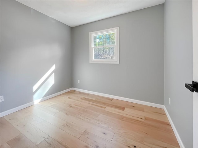 spare room featuring light wood-style floors and baseboards