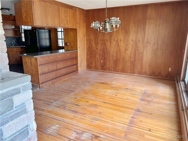 6449 W Scott Rd, Scott, NY 13077 - kitchen featuring freestanding refrigerator, brown cabinetry, a chandelier, light wood-style flooring, and wooden walls