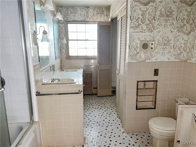 6449 W Scott Rd, Scott, NY 13077 - bathroom with tile walls, tile patterned flooring, wallpapered walls, toilet, and wainscoting