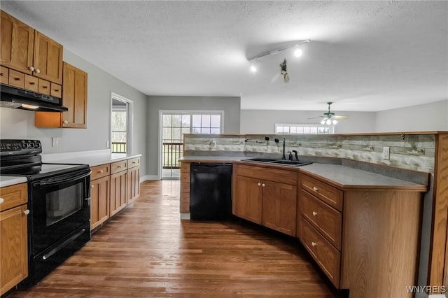 kitchen with a healthy amount of sunlight, a ceiling fan, a sink, dark wood-type flooring, and black appliances