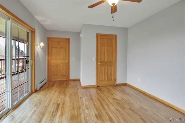 empty room featuring a baseboard heating unit, ceiling fan, baseboards, and light wood finished floors