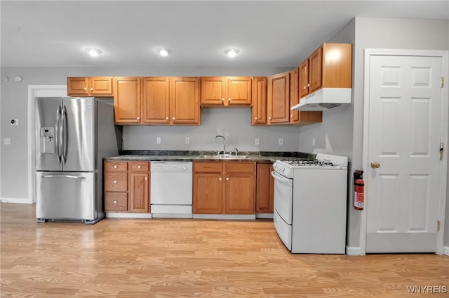 kitchen featuring under cabinet range hood, white appliances, a sink, and light wood finished floors