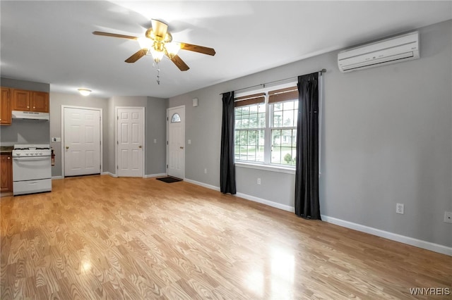 unfurnished living room featuring light wood-style flooring, a wall unit AC, baseboards, and a ceiling fan