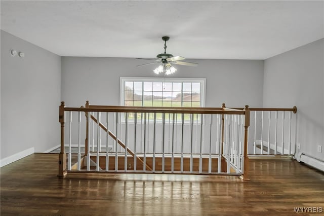interior space featuring baseboard heating, baseboards, a ceiling fan, and wood finished floors