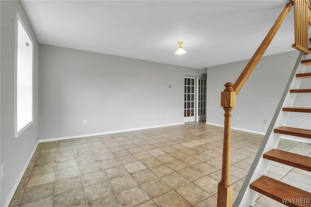 unfurnished living room with stairway, baseboards, and light tile patterned floors