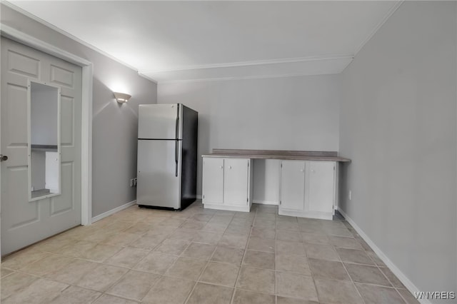 interior space featuring ornamental molding, white cabinets, freestanding refrigerator, and baseboards