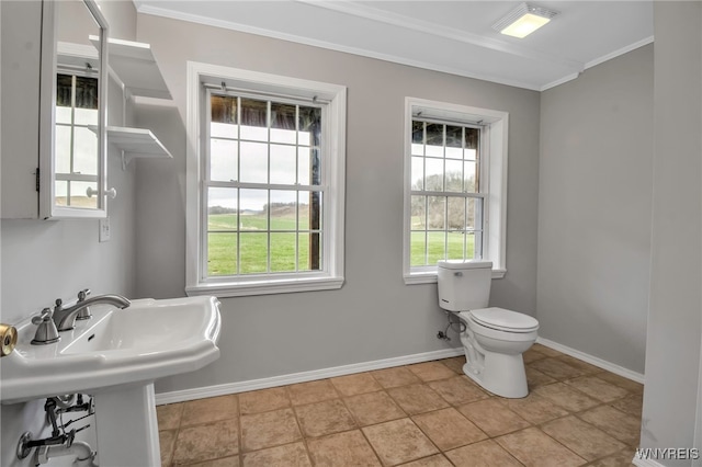 bathroom featuring crown molding, toilet, and baseboards