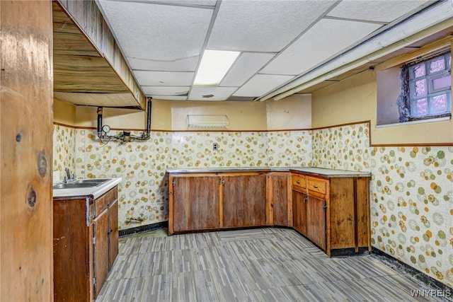 2300 Main St, Buffalo, NY 14214 - kitchen with baseboards, a sink, a paneled ceiling, brown cabinets, and wallpapered walls