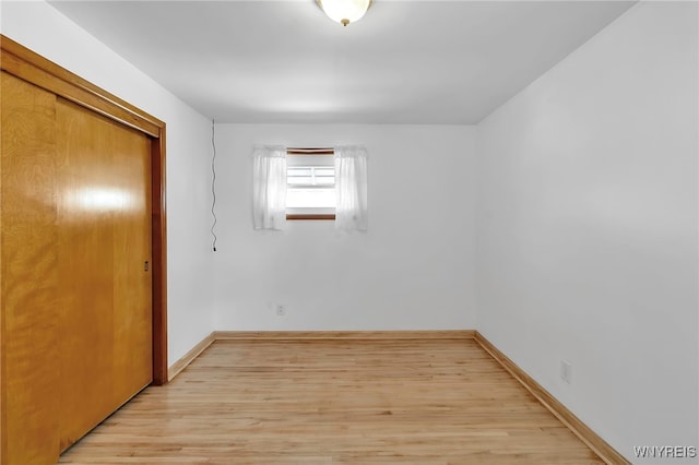 unfurnished bedroom with light wood-style flooring, a closet, and baseboards
