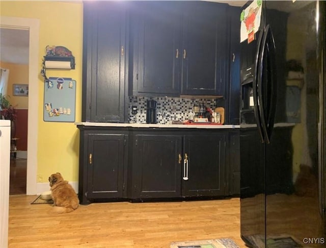 bar with backsplash, black fridge, and light wood-style floors