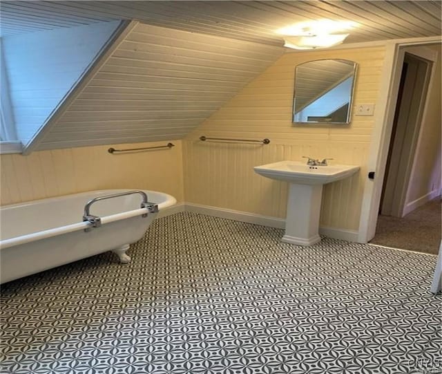 622 Fulton St, Wilna, NY 13619 - bathroom with wood walls, vaulted ceiling, wooden ceiling, a freestanding bath, and baseboards