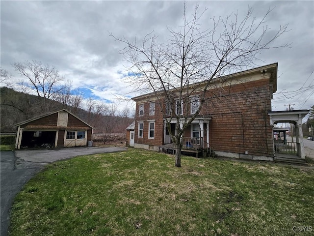 view of front of property with a front lawn, a detached garage, and an outdoor structure