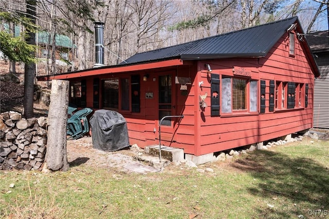 back of house featuring metal roof and a lawn