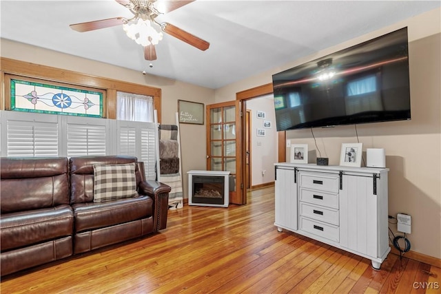 living room with light wood finished floors, baseboards, and ceiling fan