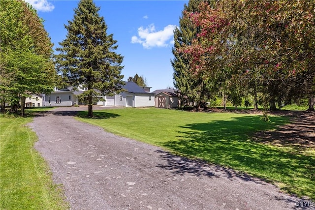 view of front of property featuring a storage shed, an outdoor structure, a front lawn, and asphalt driveway