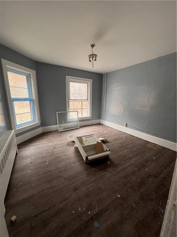 spare room with baseboards, radiator heating unit, and hardwood / wood-style floors