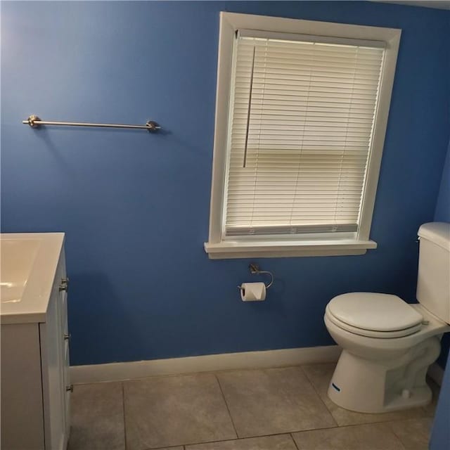 half bathroom with baseboards, toilet, vanity, and tile patterned flooring