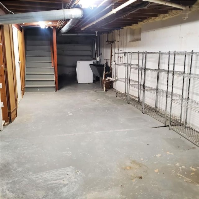 unfinished below grade area featuring washer / clothes dryer, stairway, and a sink