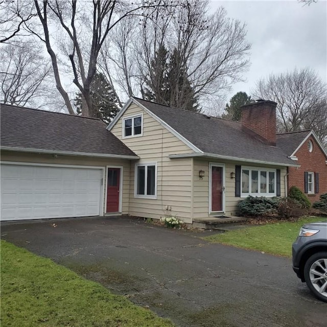 traditional home featuring asphalt driveway, a chimney, an attached garage, and roof with shingles