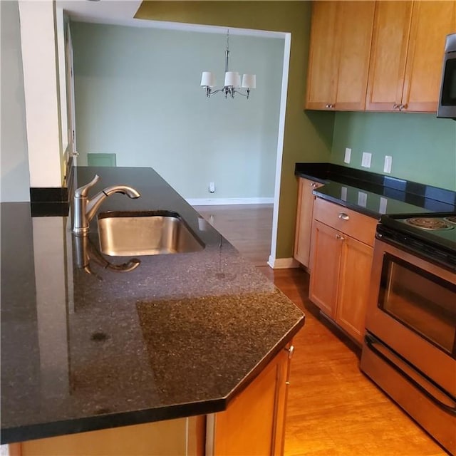 kitchen featuring stainless steel range with electric stovetop, a sink, a chandelier, baseboards, and light wood-type flooring